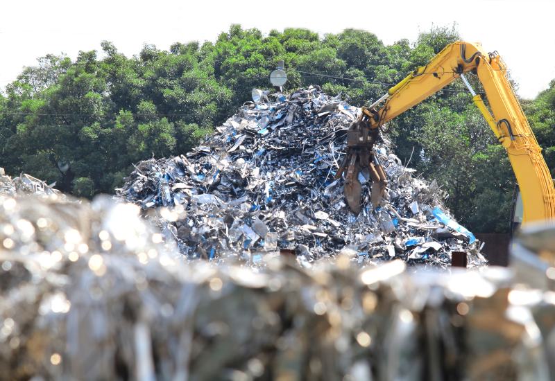 Excavator moving a large pile of scrap metal at a recycling yard in Vancouver, BC