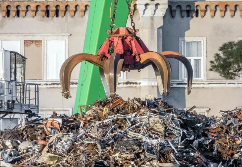A large industrial claw lifts scrap metal from a debris pile in Vancouver, BC